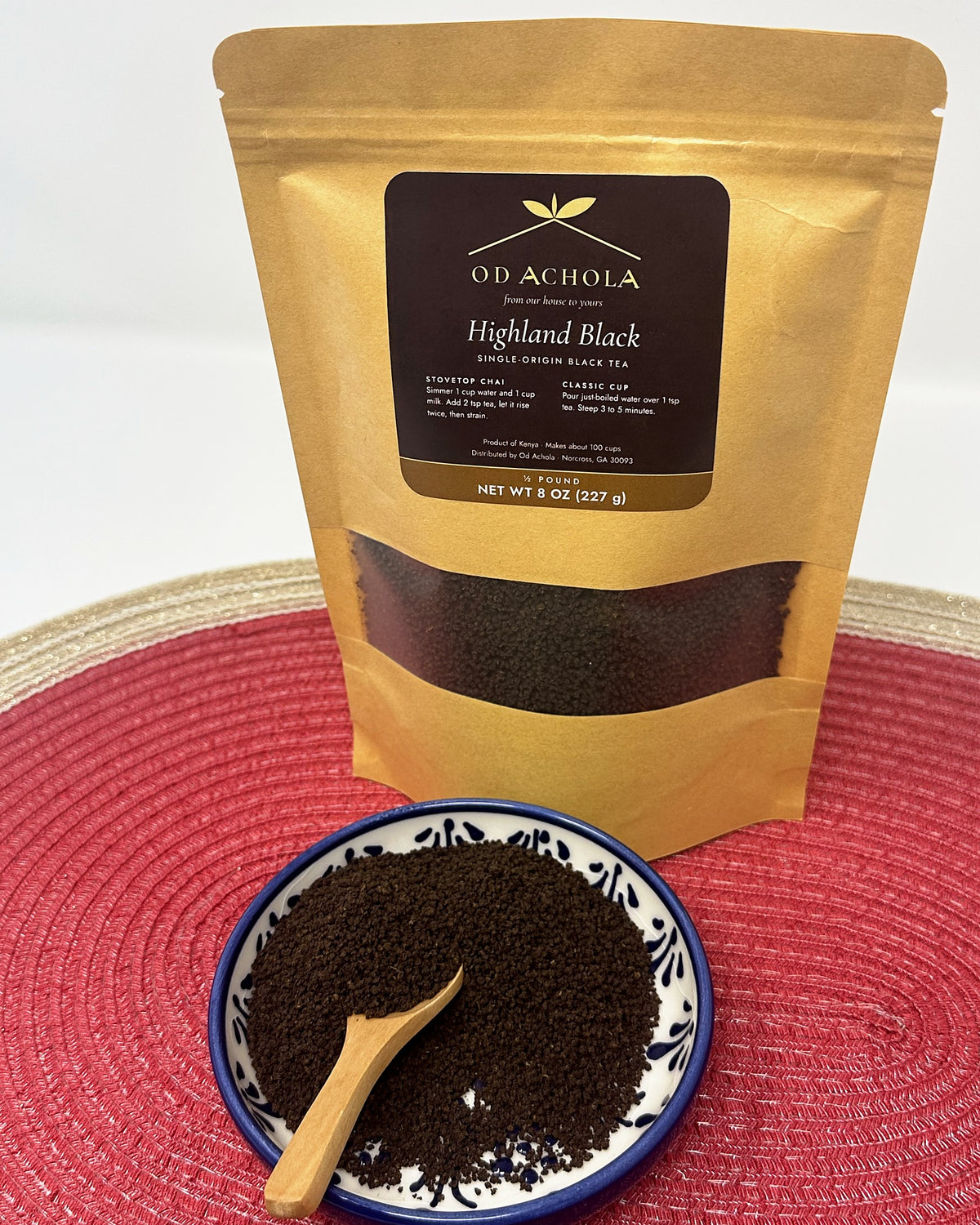 Od Achola Highland Black Kenyan black tea in a kraft pouch beside a dish of loose CTC tea and a wooden scoop