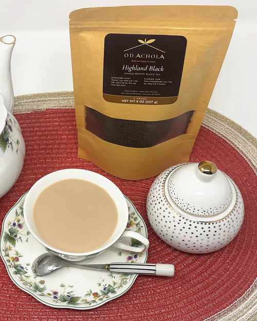 Cup of Kenyan milk chai with a floral teapot, sugar bowl and a pouch of Highland Black tea
