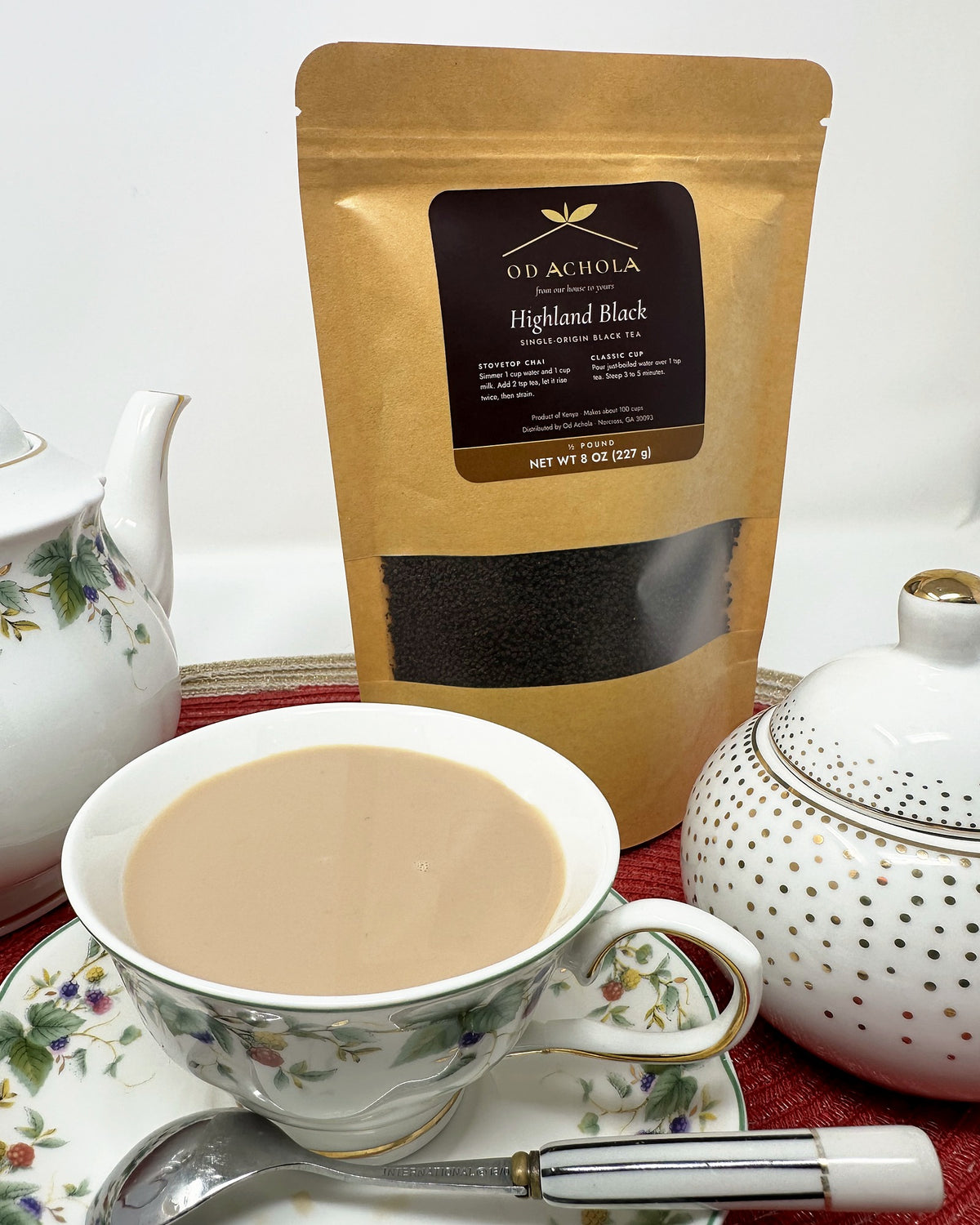 Close-up of a cup of milky chai in front of a pouch of Od Achola Highland Black tea