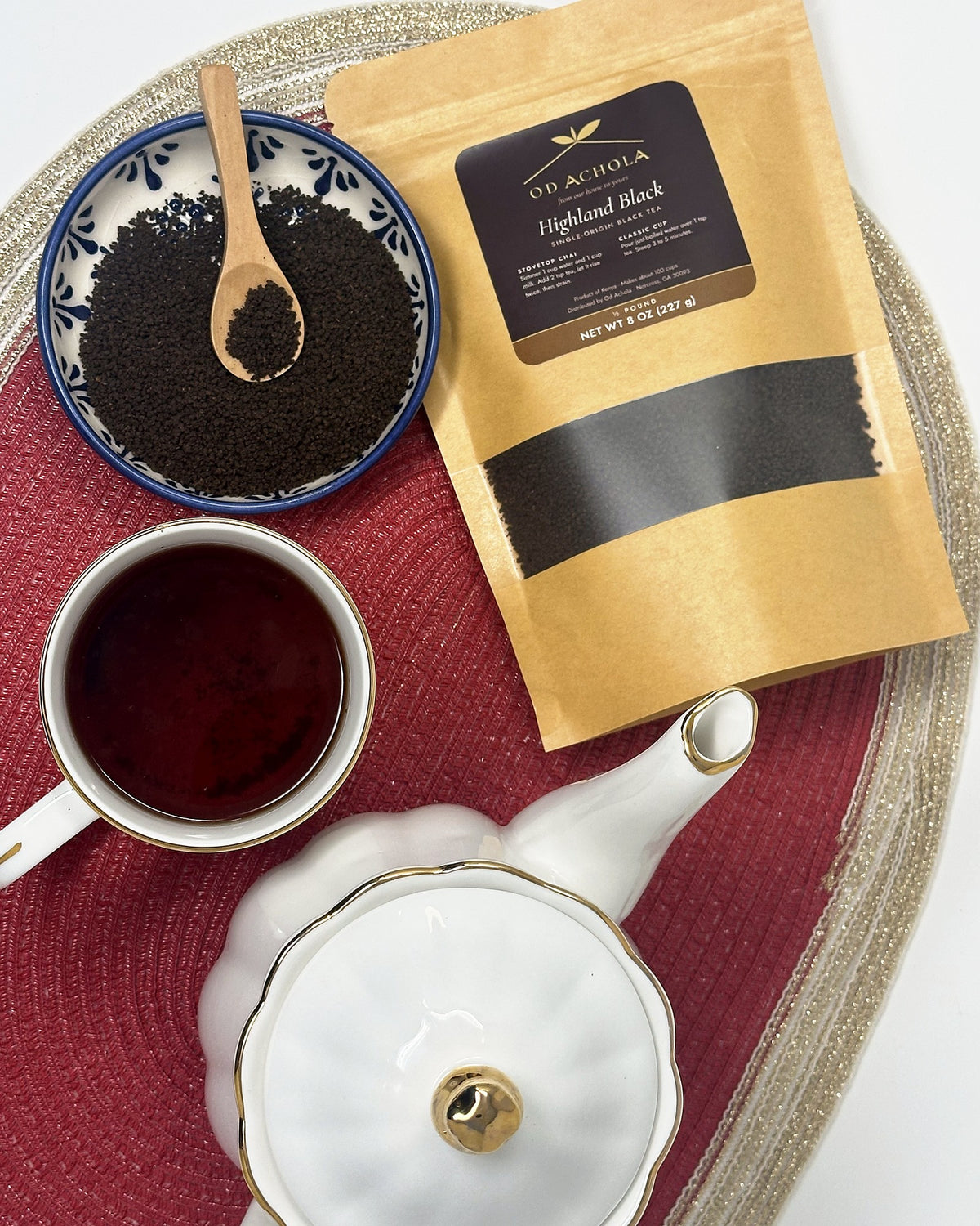 Overhead view of loose Highland Black tea, a cup of plain black tea, a teapot and the tea pouch
