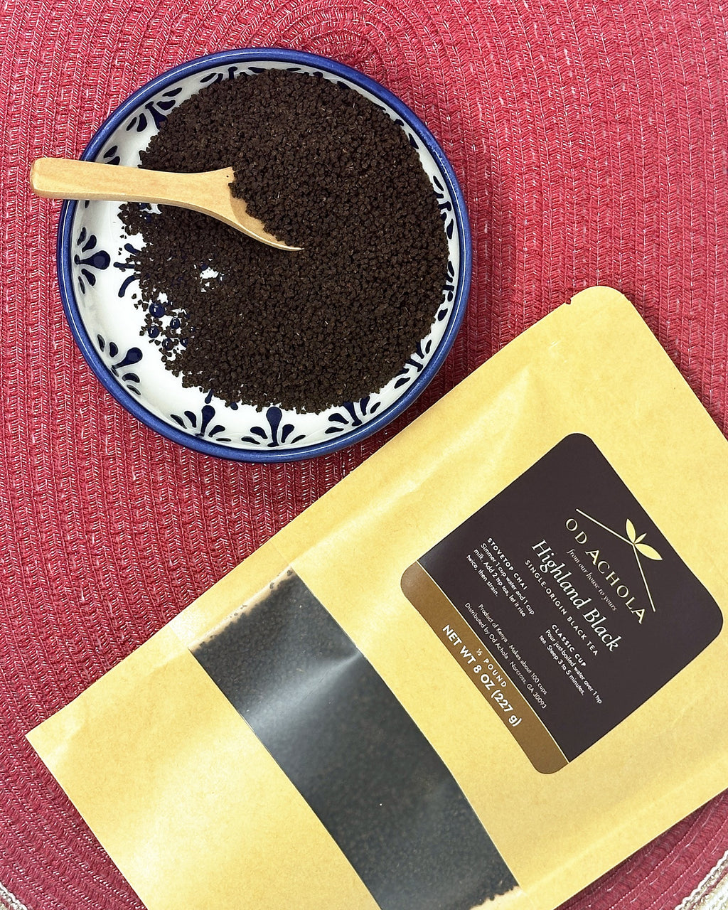 Loose Highland Black CTC tea granules in a blue and white dish next to the kraft tea pouch